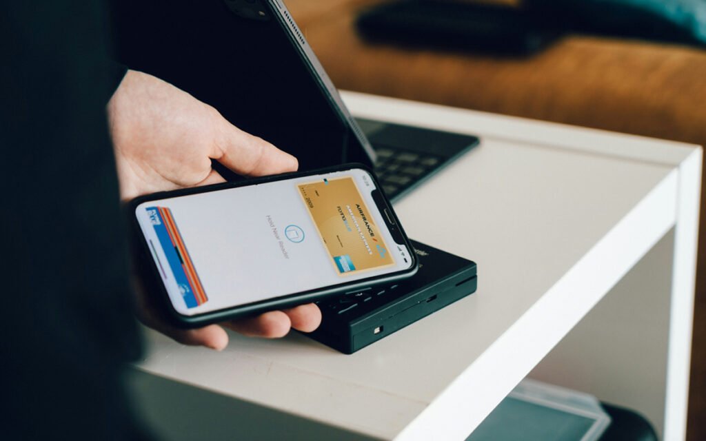 Persona utilizando una billetera digital en un smartphone mientras realiza una transferencia bancaria desde una aplicación fintech.